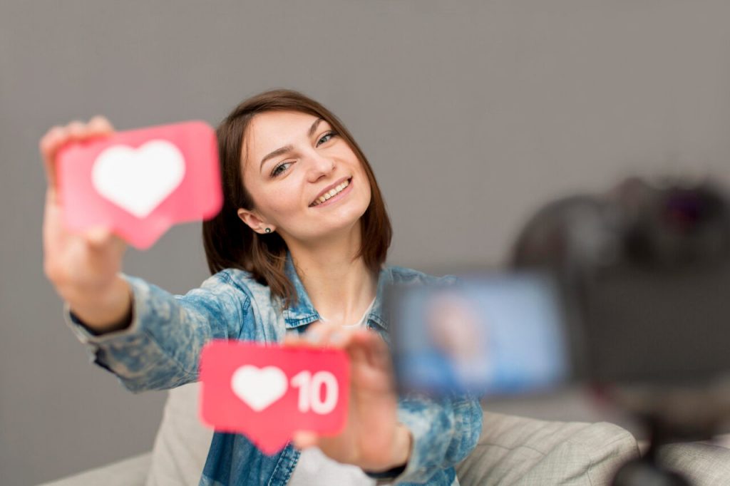 Criadora de conte&uacute;do segurando &iacute;cones de curtidas e engajamento em a&ccedil;&atilde;o de marketing digital e redes sociais