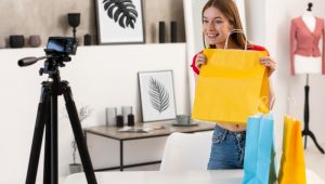 Influenciadora exibindo sacolas coloridas para a câmera, demonstrando ações de marketing promocional no varejo.