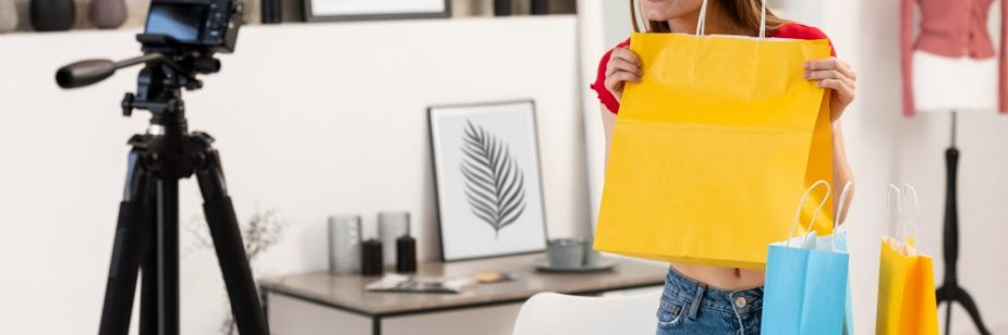 Influenciadora exibindo sacolas coloridas para a câmera, demonstrando ações de marketing promocional no varejo.