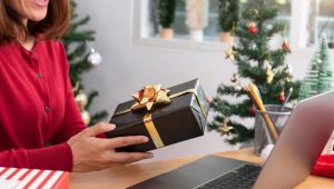 Mulher recebendo brindes gourmet em embalagem de presente