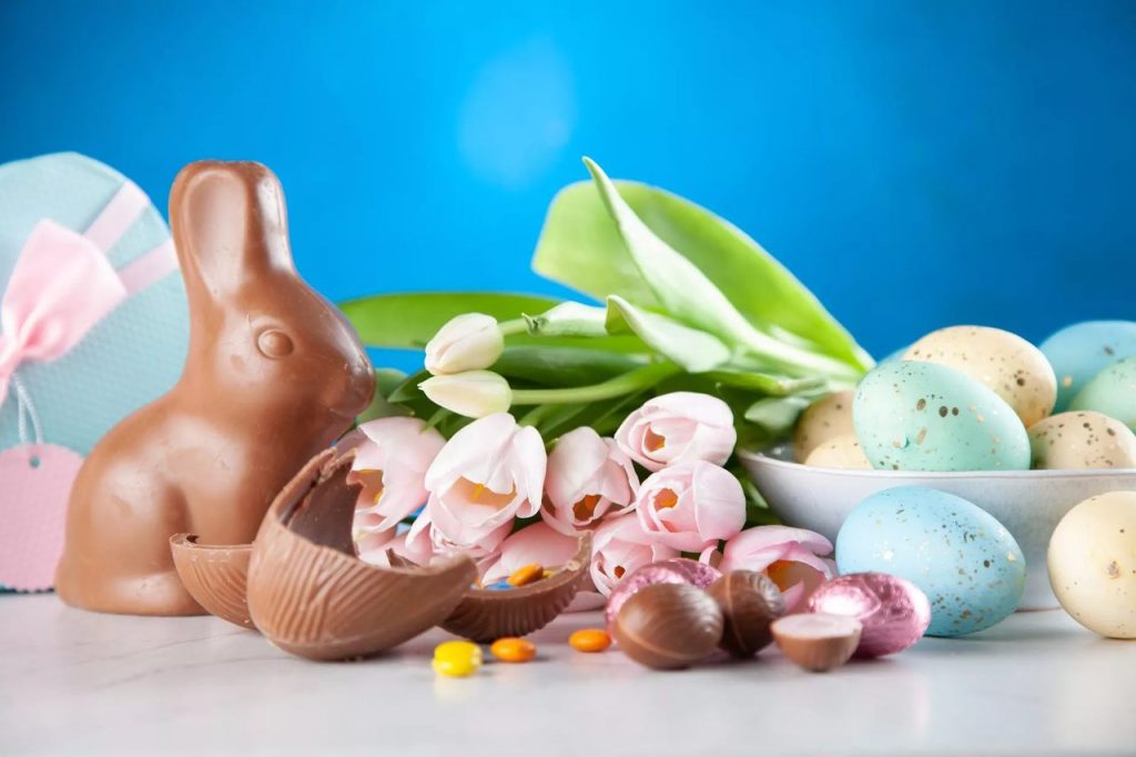 Coelhinho de chocolate, com rosas, ovinhos de chocolate e ovos coloridos enfeitados, simbolizando brindes de páscoa