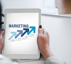 Pessoa segurando tablet com conceito de marketing e setas de crescimento representando estratégia e planejamento