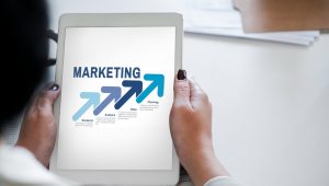 Pessoa segurando tablet com conceito de marketing e setas de crescimento representando estrat&eacute;gia e planejamento