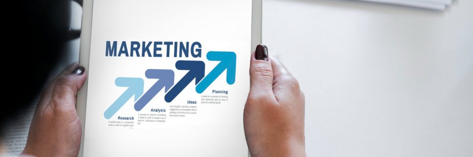 Pessoa segurando tablet com conceito de marketing e setas de crescimento representando estratégia e planejamento