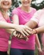 mulheres usando camisetas rosas e juntando as mãos representando ideias para outubro rosa na empresa