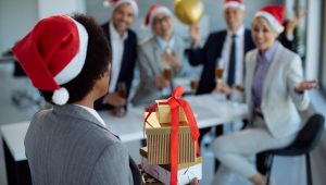 Cena de confraternização com entrega de brindes de Natal para funcionários no ambiente corporativo.