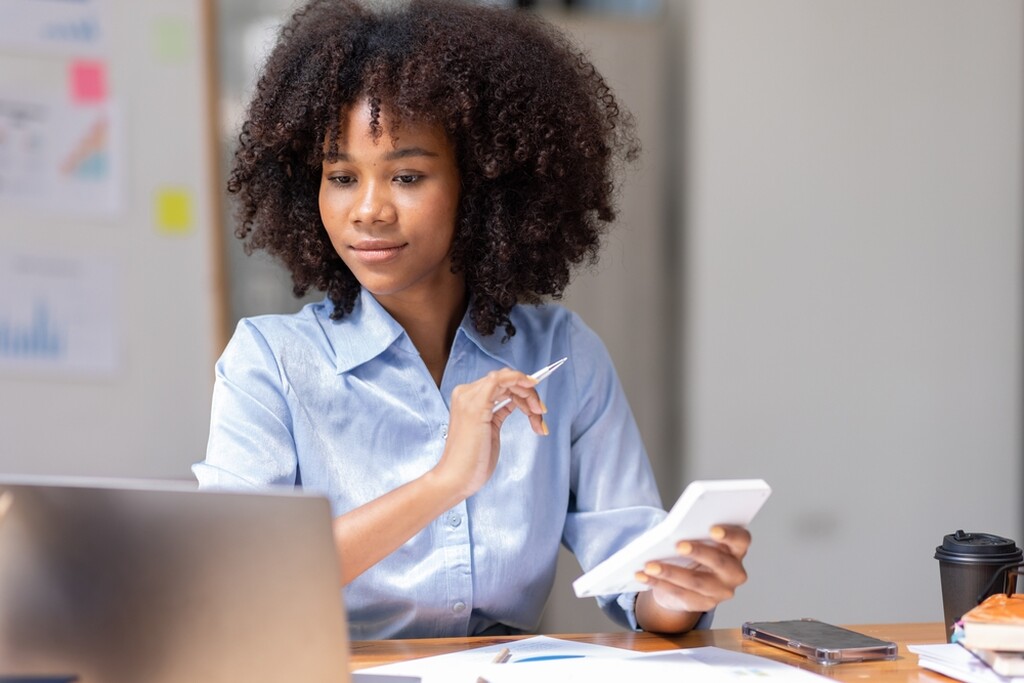 Contadora usando calculadora no escritório, representando praticidade e valorização com brindes para contadores.
