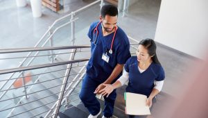 Dois profissionais de enfermagem em uniforme conversando em ambiente hospitalar, representação do impacto dos brindes para enfermagem em ações de reconhecimento.
