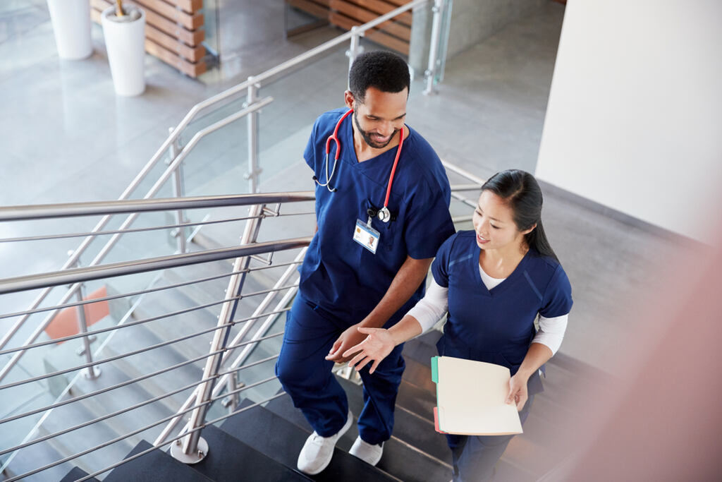 Dois profissionais de enfermagem em uniforme conversando em ambiente hospitalar, representação do impacto dos brindes para enfermagem em ações de reconhecimento.