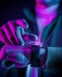 Pessoa ajustando um smartwatch com iluminação neon colorida, demonstrando tecnologia wearable moderna em um ambiente escuro.